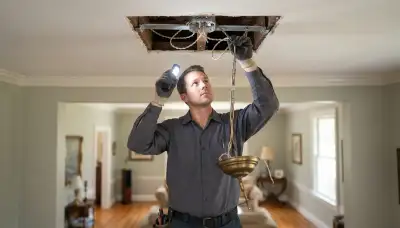 Electrician assesses ceiling box and support brace for chandelier installation in Richmond, VA homes
